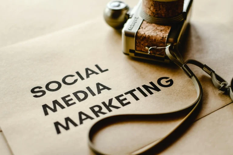 a camera placed beside a notebook with the words 'social media marketing' provided by freelance digial marketer in kannur